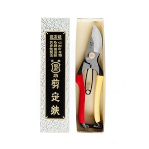 May include: A pair of red and yellow pruning shears in a white box with Japanese text. The text on the box reads "飛庄" and "剪定鋏".