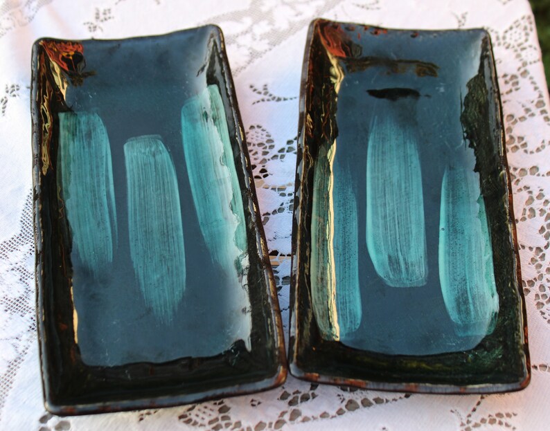May include: Two rectangular ceramic serving dishes with a dark green glaze and a light green brushstroke design.