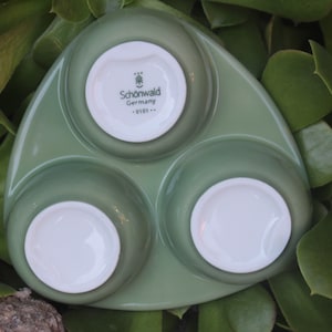 May include: A green ceramic serving dish with three individual bowls. The center bowl has a white label with the text "Schonwald Germany -9101-."