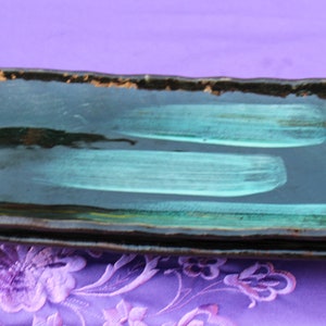 May include: A set of three black and teal rectangular ceramic serving dishes. The dishes are stacked on top of each other.