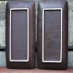 May include: Two rectangular brown ceramic serving trays with white trim. The trays have a textured surface.