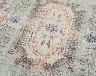 May include: A vintage rug with a faded floral pattern in shades of blue, pink, and green. The rug has a distressed look and a worn texture.