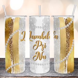 Puede incluir: Tres vasos de acero inoxidable con diseños de purpurina dorada y blanca. Los vasos tienen un diseño de purpurina dorada y blanca con una cuerda de perlas envuelta alrededor del vaso. El vaso del medio tiene el texto "Lambda Psi Nu" en letras doradas.