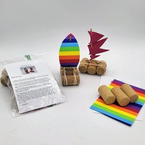 Pode incluir: Kit de artesanato para fazer um barco de cortiça com instruções. O kit inclui velas de espuma coloridas, flutuadores de cortiça e elásticos. As instruções mostram como montar o barco e incluem um guia passo a passo.