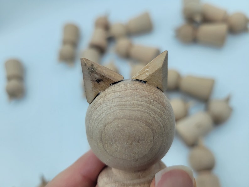 May include: A wooden toy with a round body and two triangular ears. The toy is made of light brown wood and has a smooth finish.