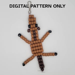 May include: A beaded lizard keyring in shades of brown, black, and tan. The lizard is made of small, square beads strung together, with a silver clasp at the top. The text "DIGITAL PATTERN ONLY" is above the lizard.