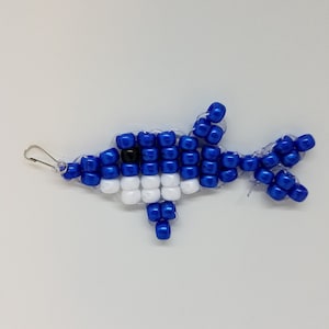 Peut inclure: Un dauphin en perles bleues et blanches avec un &oelig;il noir. Le dauphin est fait de petites perles rondes et a une boucle en haut pour l'accrocher.