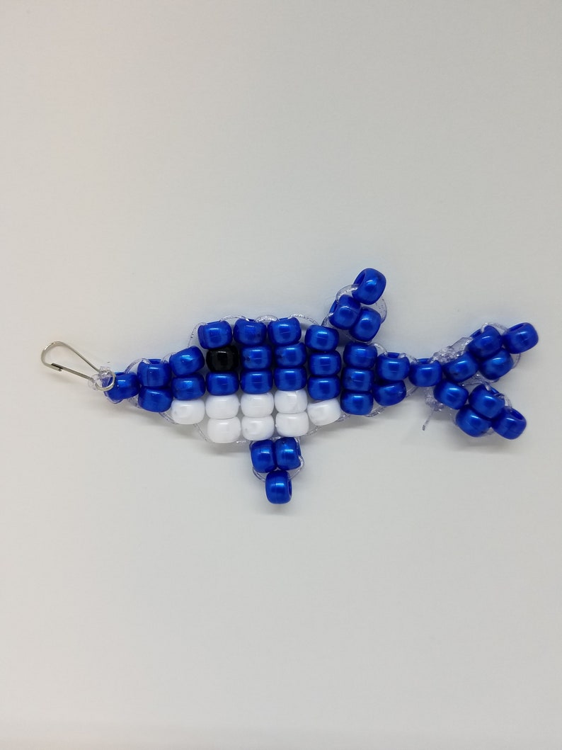 Peut inclure: Un dauphin en perles bleues et blanches avec un &oelig;il noir. Le dauphin est fait de petites perles rondes et a une boucle en haut pour l'accrocher.
