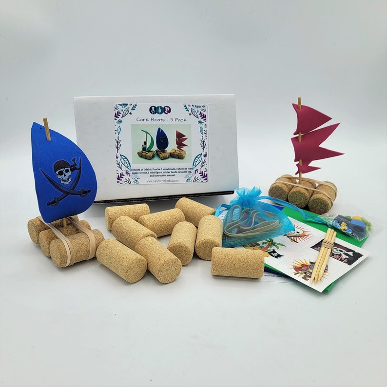 May include: A set of cork boats for kids to make. The set includes 4 cork boats, 1 wood mast, 1 sail, 1 rubber band, 1 wooden dowel, 1 wooden flag, 1 pirate flag, 1 pirate skull and crossbones, 1 instruction sheet, and 1 bag of colorful beads. The set is packaged in a box with the words "Cork Boats - 4 Pack" printed on it.