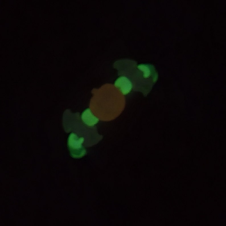 May include: A glow-in-the-dark fidget toy shaped like a bat with a yellow center.
