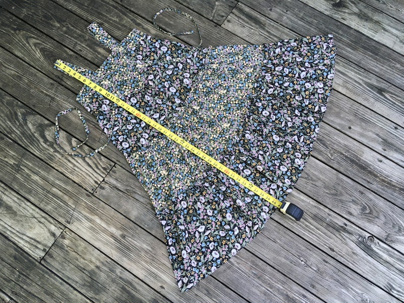 Puede incluir: Un vestido negro con estampado floral con una cinta m&eacute;trica amarilla colocada encima. El vestido presenta un patr&oacute;n de peque&ntilde;as flores blancas, azules y amarillas. La cinta m&eacute;trica muestra una longitud de aproximadamente 122 cm.
