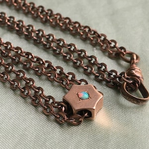 May include: A gold chain with a star-shaped pendant featuring a small opal gemstone. The chain has a hook clasp.