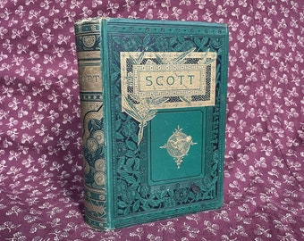 May include: A vintage green hardcover book with gold accents and the word "SCOTT" embossed on the front cover. The book is sitting on a burgundy fabric with a white floral pattern.