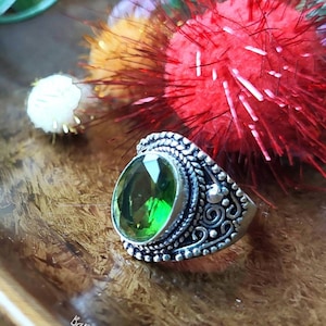 Puede incluir: Un anillo de plata con un diseño adornado y una gran piedra preciosa verde de forma ovalada.