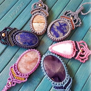 May include: Six macrame pendants with different colored stones. The stones are set in a macrame design with a variety of colors including purple, pink, blue, brown, and gold.