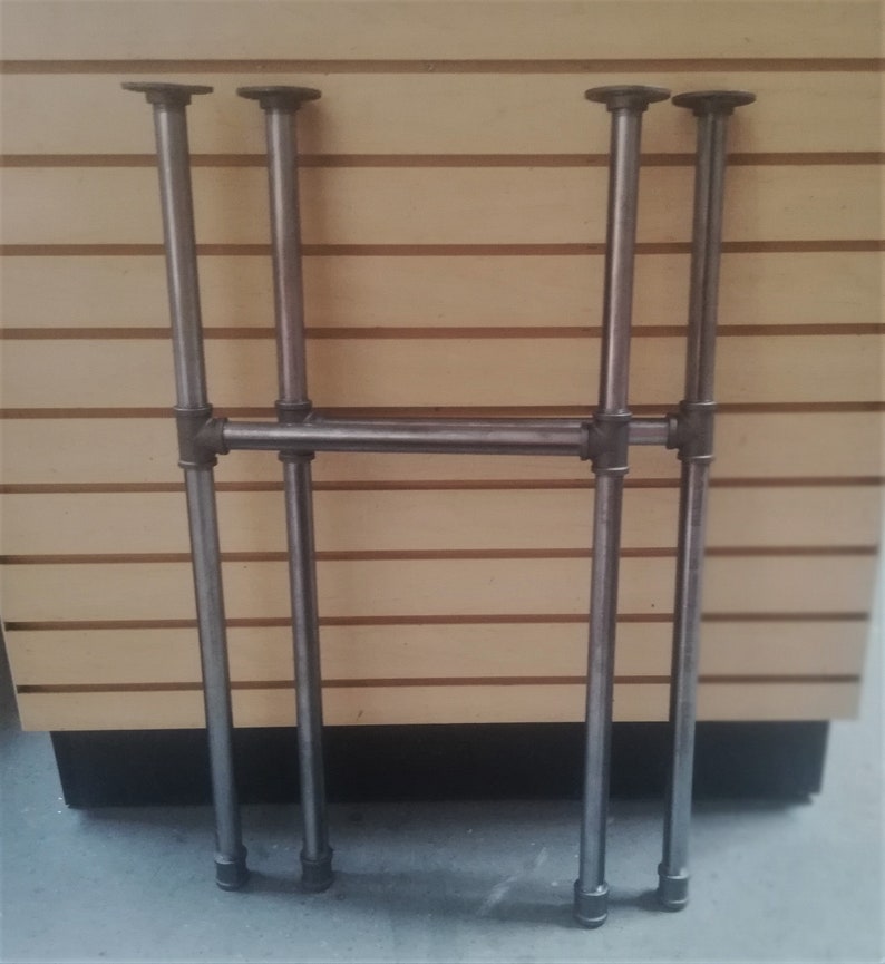 May include: A set of four metal pipe legs for a table or shelf. The legs are made of black metal pipe and have a simple, industrial design.