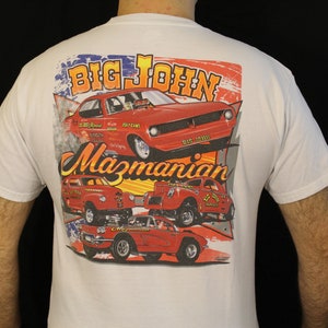 May include: White t-shirt featuring a colorful graphic of vintage red race cars with the text "BIG JOHN Mazmanian". The design includes an American flag motif and various car models, perfect for car enthusiasts.
