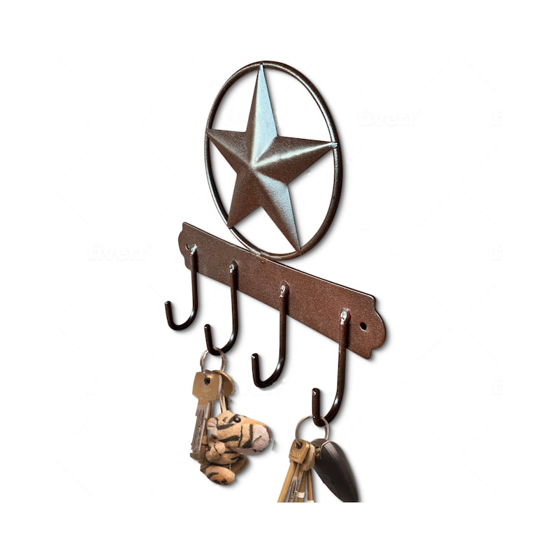May include: A rustic metal key holder with four hooks and a star-shaped design. The key holder is painted in a brown color and has a distressed finish. The star is silver and is surrounded by a circle.