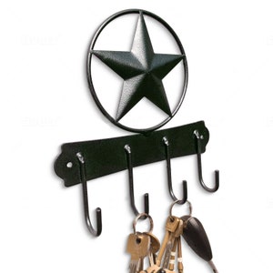 May include: Black metal key holder with a five-pointed star design. The holder has four hooks and is mounted on a wall.