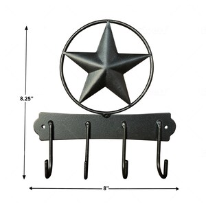 May include: Black metal key hook with three hooks and a star-shaped design. The hook measures 8 inches wide and 8.25 inches tall.