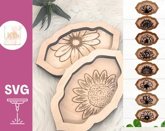 May include: Two wooden trays with laser-cut designs of sunflowers and daisies. The trays are on a white fuzzy surface. There are eight additional laser-cut designs of various flowers in a vertical row on the right side of the image. The text "SVG" and a laser cutter icon are in the lower left corner. The text "Digital Files for Laser Cutters" is at the bottom of the image.