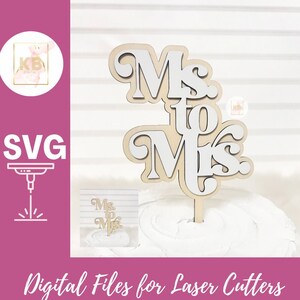 May include: A wooden cake topper with the words "Mrs. to Mrs." in a white and brown layered design. The topper is perfect for a wedding or engagement celebration.