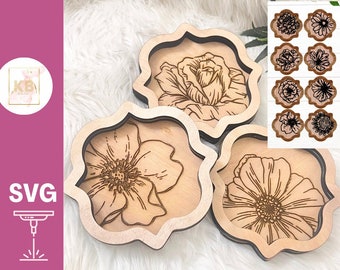 May include: Three wooden coasters with intricate floral designs laser cut into the wood. The coasters are in the shape of a flower with a rounded edge. The designs are of different flowers, each with a unique pattern.