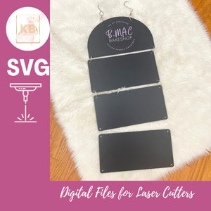 May include: Black laser-cut sign with the text "B.MAC BAKESHOP CUSTOM FRENCH MACARONS" and "Digital Files for Laser Cutters". The sign is hanging from two silver hooks. The sign is made of several rectangular pieces.