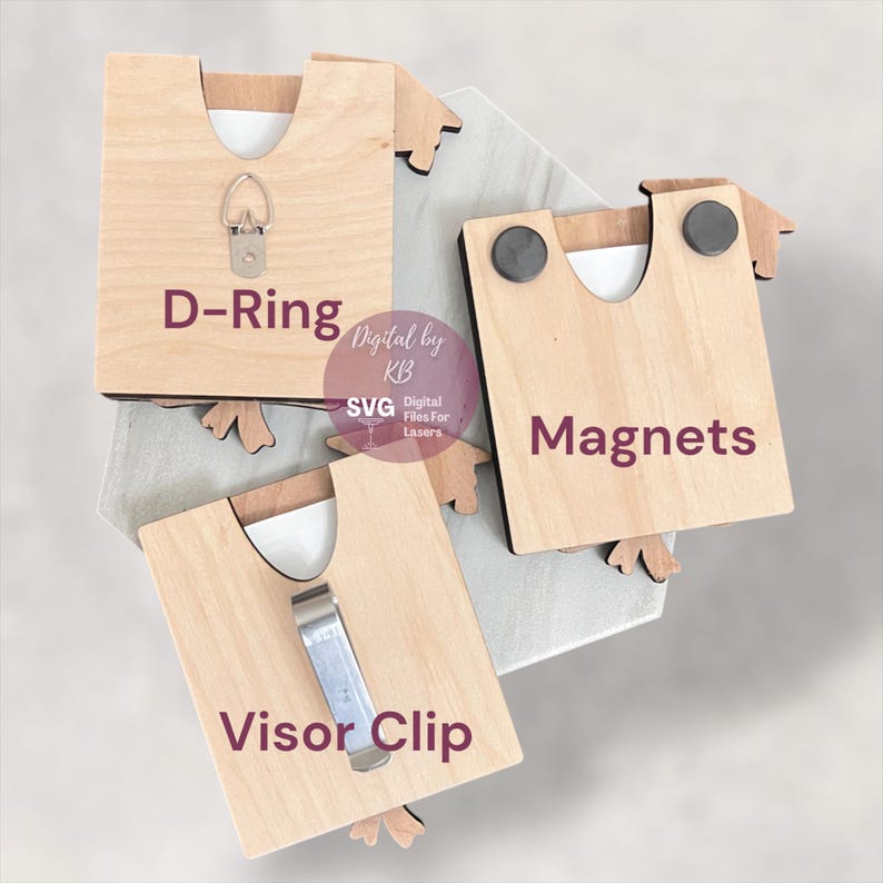 May include: Three wooden graduation cap ornaments with different hanging options: a D-ring, magnets, and a visor clip.  The text "Digital by KB" and "SVG Digital Files for Lasers" is printed on the ornaments.