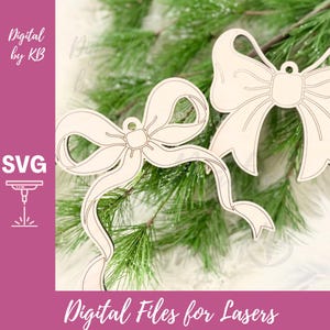 May include: Two wooden bow ornaments with intricate cut-out details, perfect for holiday decor. The bows are light-colored, possibly unfinished wood, and are set against a backdrop of green pine branches. The image includes the text "Digital Files for Lasers".