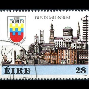 Pode incluir: Um selo postal irlandês vintage que apresenta uma ilustração colorida do horizonte de Dublin. O selo é azul, branco e vermelho com o texto "DUBLIN MILLENNIUM" e "ÉIRE" impresso nele. O selo também apresenta o texto "1988 DUBLIN" e "28".