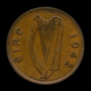 Może przedstawiać: Brązowa irlandzka moneta z 1942 roku, z motywem harfy pośrodku. Słowo "EIRE" jest wyryte po lewej stronie, a rok "1942" po prawej. Moneta ma teksturowaną krawędź i ciemne tło.