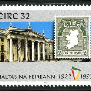 Puede incluir: Un sello postal con el texto "ÉIRE 32" y una imagen de un edificio. Un sello más pequeño muestra un mapa de Irlanda. El texto "RIALTAS NA HÉIREANN 1922 1997" también es visible. El sello tiene un diseño verde, blanco, rojo y amarillo.