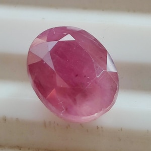 May include: A pink oval-shaped gemstone with a faceted cut.