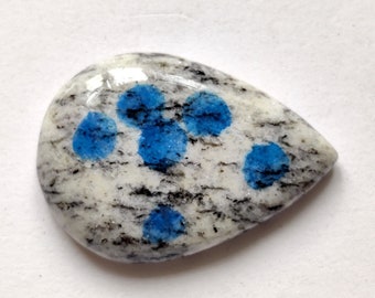 May include: A white and gray cabochon with blue spots, a type of gemstone.
