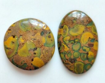 May include: Two round and oval shaped cabochons of green, brown, and yellow jasper. The stones have a mottled pattern.