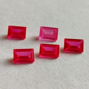 May include: Five pink rectangular gemstones with a faceted cut.