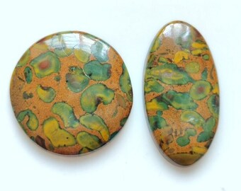 May include: Two polished gemstones. One is round, the other is oval. Both have a brown base colour with green, yellow, and red patterns. The gemstones are set against a white background.