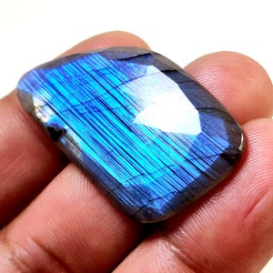 May include: A large, iridescent blue labradorite gemstone with a rectangular shape. The stone has a unique, shimmering effect that is characteristic of labradorite.