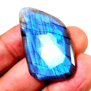May include: A blue and iridescent labradorite gemstone with a smooth, polished surface. The stone has a unique, natural pattern of lines and swirls.