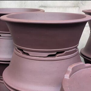 May include: A set of three brown terracotta pots, stacked on top of each other. The pots are unglazed and have a rough texture.