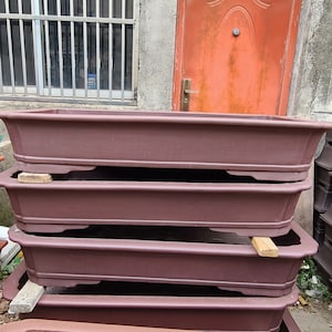 May include: Four brown rectangular ceramic planters stacked on top of each other. The planters have a slightly flared lip and a rounded base.