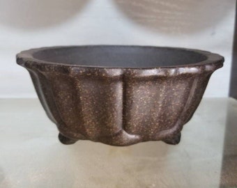 May include: A brown ceramic bonsai pot with a scalloped rim and three legs.