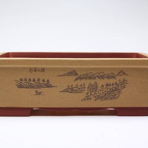 May include: A rectangular bonsai pot with a brown glaze and a landscape design. The pot has a red rim and feet.