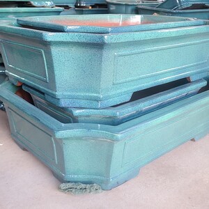 May include: Three stacked rectangular ceramic planters in a teal green color. The planters are made of glazed ceramic and have a textured surface.