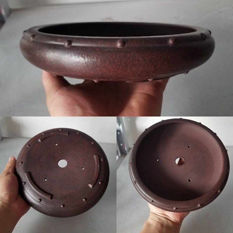 K&ouml;nnte beinhalten: Ein dunkelbrauner Keramik-Bonsai-Topf mit einer strukturierten Oberfl&auml;che und einem erh&ouml;hten Rand mit kleinen dekorativen Nieten. Der Topf hat eine runde Form und ein Abzugsloch im Boden.