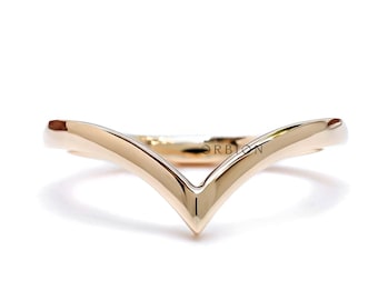 May include: A gold-toned V-shaped wedding band. The band is smooth and polished.