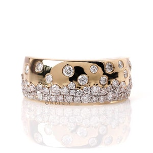 Könnte beinhalten: Ein Goldring mit einer Reihe kleiner Diamanten und einer Reihe größerer Diamanten, die in eine strukturierte Goldband gefasst sind. Der Ring befindet sich auf einem weißen Hintergrund.