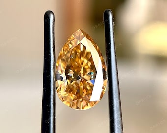 May include: A pear-shaped, golden-yellow gemstone held in a pair of tweezers. The gemstone has a brilliant cut and facets that reflect light.