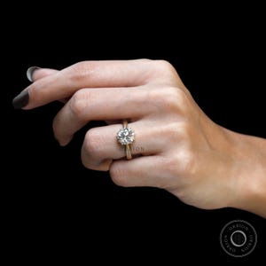 May include: A gold engagement ring with a large, round, clear diamond set in a halo setting.
